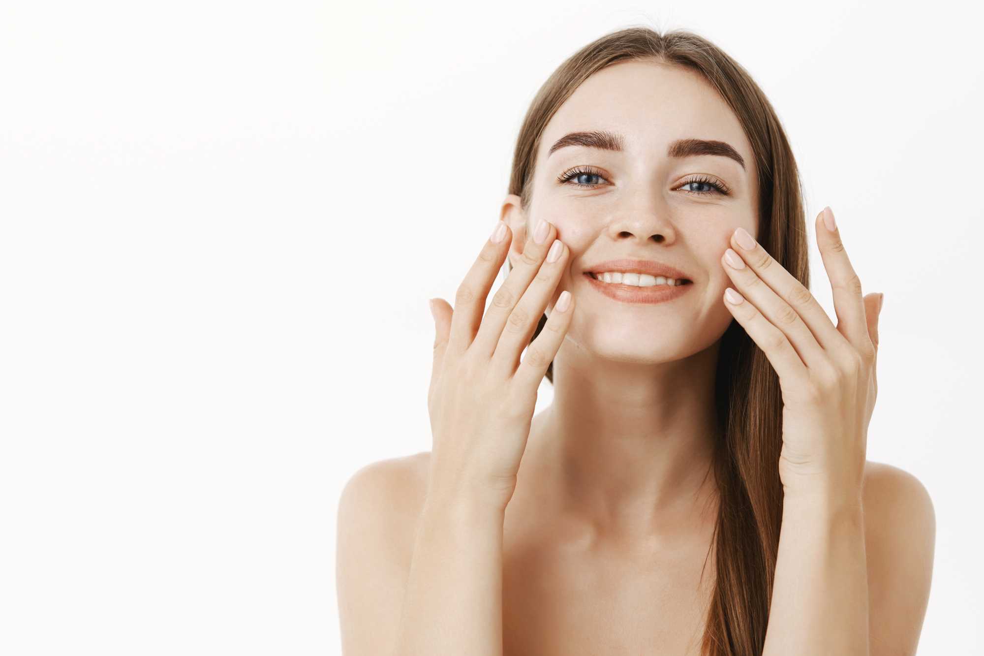 encantadora-mujer-joven-relajada-suave-haciendo-procedimiento-cosmetologico-aplicando-crema-facial-cara-dedos-sonriendo-ampliamente-sintiendose-perfecta-cuidando-piel